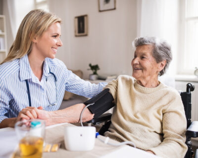 health visitor measures blood pressure in a senior woman