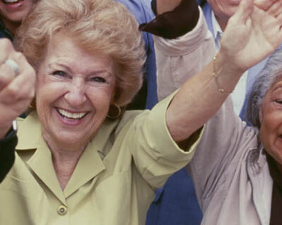 Large group of multi-ethnic people cheering with arms raised