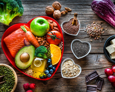 Healthy eating: group of fresh multicolored foods to help lower cholesterol levels and for heart care shot on wooden table. The composition includes oily fish like salmon. Beans like Pinto beans and brown lentils. Vegetables like garlic, avocado, broccoli, eggplant and tomatoes. Fruits like apple, grape, orange and berries. Nuts like almonds and walnuts. Soy products like tofu and soybeans. Cereals and seeds like chia seeds, flax seeds, oatmeal and barley. Olive oil, dark chocolate and yogurt with added sterols and stanols. High resolution 42Mp studio digital capture taken with SONY A7rII and Zeiss Batis 40mm F2.0 CF lens